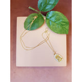 Guldbelagt halskæde med emblem der forestiller en budda den har små sten hele vejen rundt set liggende så man kan se den lange kæde