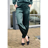 Shiny satin bukser i en flot dyb petroleumsgrøn farve bukserne har elastik og snøre i livet samt lommer i siden buksebenet afsluttes ligeledes med elastik set forfr