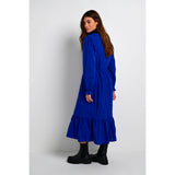 Slå-om kjole fra Kaffe i en dyb blå farve med flæser overskæringer og lange ærmer ligeledes med flæser set fra siden på model