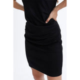 Klassisk sort kjole fra Kaffe med rund hals drapperede fortil der camouflere maven og lynlås i siden set forfra tæt på draperinger