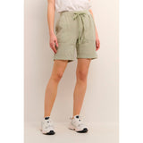 Lækre bløde shorts fra Kaffe i en flot støvet grøn farve de har elastikkant ribkanter bindebånd og dybe lommer i siden set helt tæt på Kaffe model