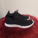 sorte sneakers med snøre og hvide såler set fra siden