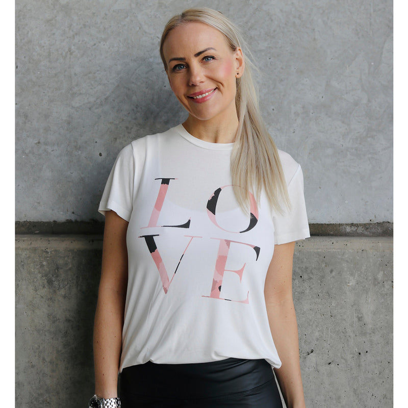 råhvid t-shirt med rund hals og korte ærmer med tekst foran i lyserød og sort leo print set forfra med by asbæk model