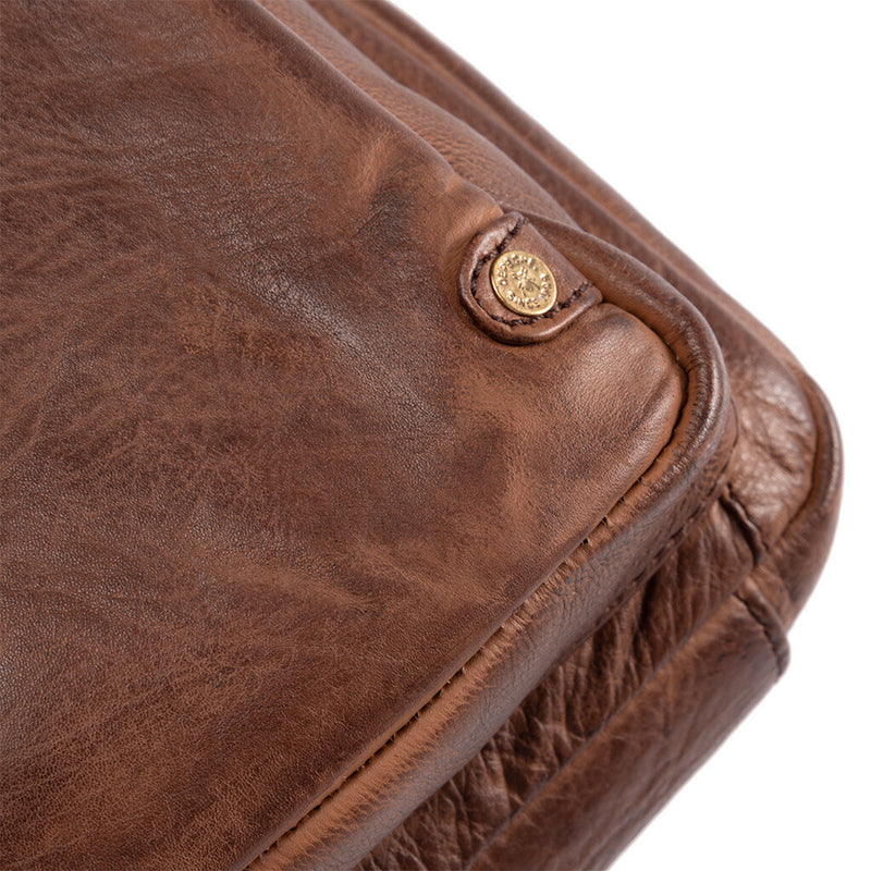 Cognac farvet læder taske med et stort og mindre rum den har justerbar rem set tæt på emblem