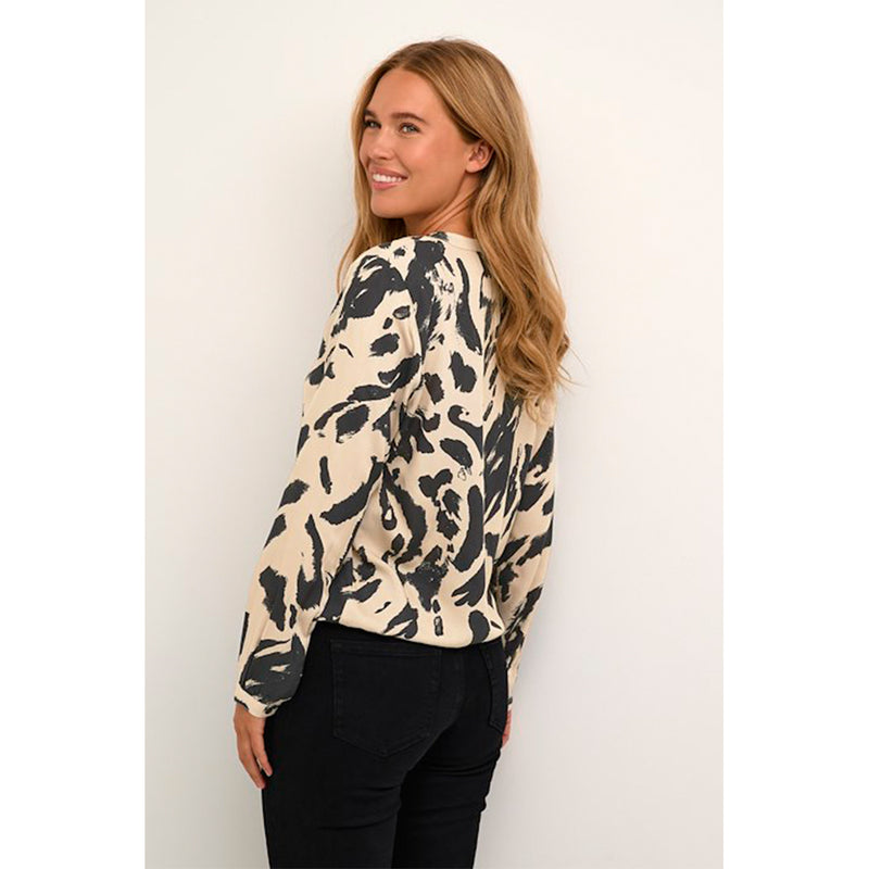 Sand farvet bluse i et sort leo print den har v-udskæring og lange ærmer som afsluttes med smal fast manchet og knap set fra siden på kaffe model