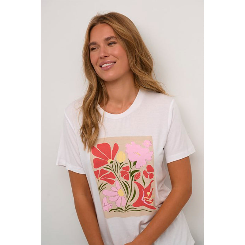 Hvid t-shirt med blomsterprint i rosa og orange den har rund hals og korte ærmer set tæt på kaffe model