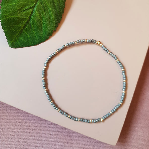 gråt elastik armbånd med guld perler set oppefra