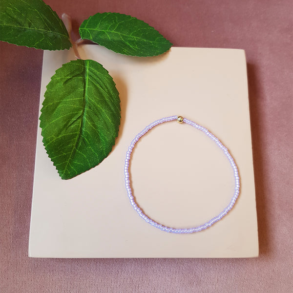 lyslilla elastik armbånd med guld perle set oppefra