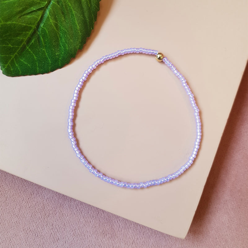 lyslilla elastik armbånd med guld perle set oppefra
