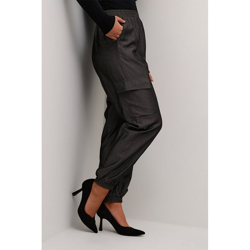 Mørkegrå bukser med udvendige lommer og elastik i taljen og benene set fra siden