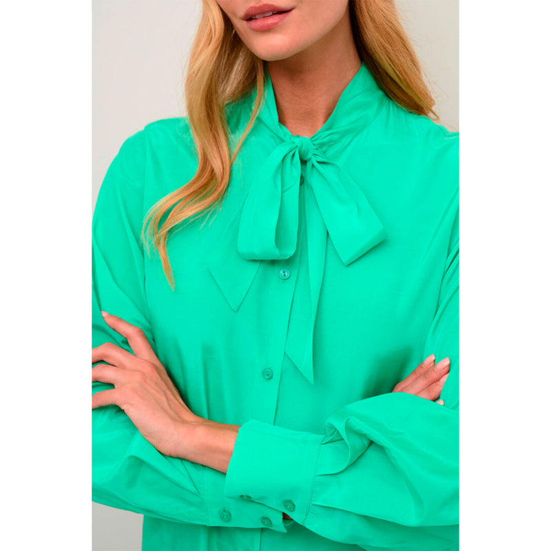 Shiny grøn skjorte som er gennemknappet med små knaiier den har skjorte i halsen og lange ærmet med fast manchet set tæt på sløjfe