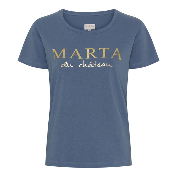 MARTA DU CHÀTEAU JEANETTE TEE DENIM BLUE  Blød bomulds t-shirt fra Marta i en denim blå farve. T-shirten har et guld tryk på brystet, hvor der står "Marta du Chàteau". Den bløde t-shirt har en bred rund hals og en løs pasform.  Guld tryk på brystet med skrift "Marta du Chàteau" Bred rund hals Korte ærmer Løs pasform