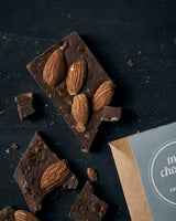 Knækket milk chocolate på bord hvor man tydeligt ser mandlerne