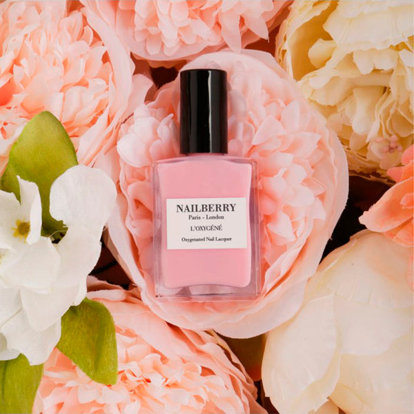 halv gennemsigtig rosa farvet neglelak og blomster baggrund set forfra