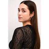 Blonde mesg bluse i sort med rund hals og lange ærmer set tæt på ærme