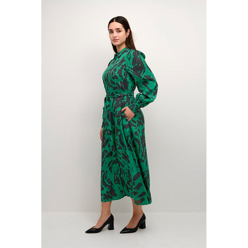 Lang grøn og gennemknappet kjole med bindebånd og lange ærmer som afslutte med smock den har almindelig skjortekrave set fra siden