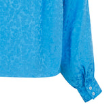 Blå bluse med struktur i materiale stolpe ned og lange ærmer set tæt på ærme
