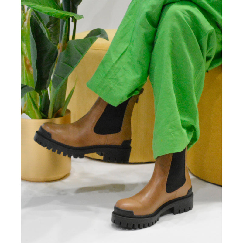 Brun kort støvle med sorte elastikker og hæl strop set fra siden på model
