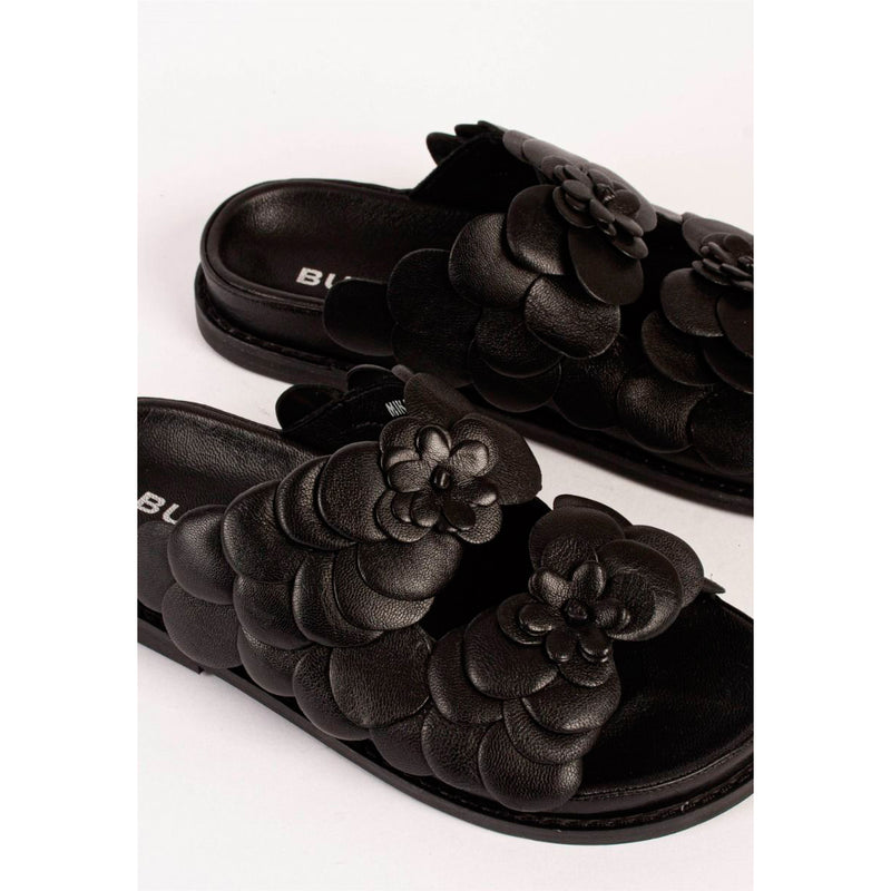 Sort sandal fra Bukela med 2 remme overdækket med sorte blomster det er en flad sandal set fra tæt på
